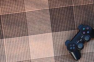 Video game controller lies on a checkered plaid photo