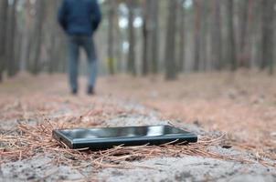 Young man loses his smartphone on Russian autumn fir wood path. Carelessness and losing expensive mobile device concept photo