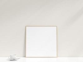 Interior poster mockup with photo frame leaning against the white wall. Minimalist photo frame mockup. Empty frame stands on white table. 3d rendering.