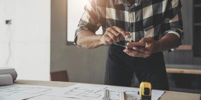 Image of engineer drawing a blue print design building or house, An engineer workplace with blueprints, pencil, protractor and safety helmet, Industry concept photo