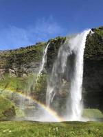 A rainbow in front of Seljalandsfoss waterfall on the southern coast of Iceland on a sunny day photo