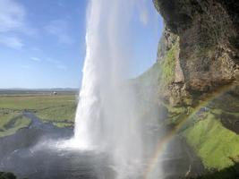 un arco iris frente a la cascada seljalandsfoss en la costa sur de islandia en un día soleado foto