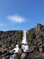 una gran cascada sobre un acantilado rocoso - oxarafoss en el parque nacional de Thingvellir. foto