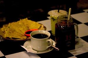 photo of food and drinks on the table in a cafe at night