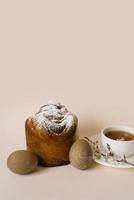 An Easter composition with a cake and eggs and a cup of tea with a sprig of a flowering apple tree on a light background. Easter vacation breakfast concept with copy space. photo