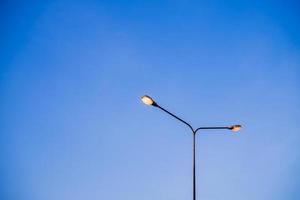 Electricity Lighting Lamp Pole Beside Road with Blue Sky, Evening Travel with Yellow Light by Electric Power Lamppost Abstract Background Concept with Copy space photo