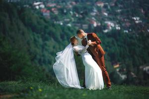 happy stylish bride and groom running and having fun in mountains on summer sunny day. gorgeous newlywed couple laughing, true feelings. emotional romantic moment. photo