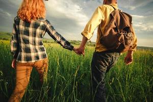 amorosa pareja hipster caminando en el campo, besándose y tomándose de la mano, abrazándose, tumbada en la hierba en el verano al atardecer. día de San Valentín
