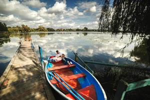 A couple riding a blue boat on a lake. romance. emotional couple. funny and in love photo