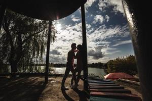 la silueta de una joven pareja amorosa se está divirtiendo al aire libre. amor y ternura, citas, romance, concepto de familia foto