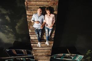 Beautiful young couple lies on a wooden bridge on the lake, looks lovingly at each other and smiles. Love story. photo