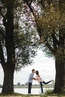 una joven pareja romántica se divierte en un día soleado de verano cerca del lago. disfrutando de pasar tiempo juntos en vacaciones. hombre y mujer se abrazan y besan. foto