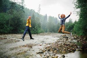 juguetona pareja feliz y guapa teniendo mientras camina en el bosque. turistas en las montañas. concepto de aventura en la naturaleza. foto