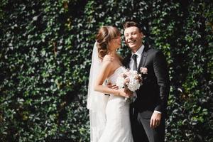 Closeup Portrait of wedding bride and groom with bouquet posing. Bridal couple, Happy Newlywed woman and man hugging. Bride and groom photo