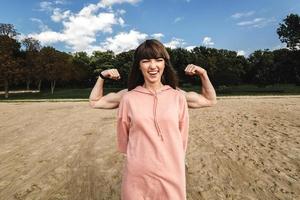 Sporty energetic athletic woman wears pink sports top smiles as shows her biceps, likes sport and active lifestyle. photo