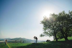 happy stylish bride and groom running and having fun in mountains on summer sunny day. gorgeous newlywed couple laughing, true feelings. emotional romantic moment. photo