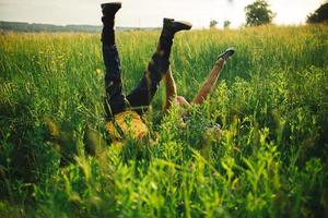 woman and man having fun outdoors. Loving hipster couple walking in the field, kissing and holding hands, hugging, lying in the grass and lifting their legs up in the summer at sunset. valentines day photo