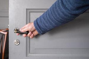 la mano abre una puerta gris de madera, en el interior. foto