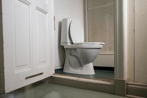 Toilet bowl with flush tank and shower in the bathroom, in a cheap hotel room. photo