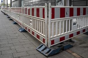 warning fencing around renovations on a pedestrian street near the road next to a building photo