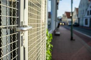 puerta de celosía de acero cerrada con manija de empuje y cerradura de mortaja que protege la puerta en una calle de la ciudad. foto