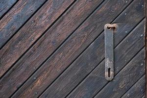 Wooden door with a metal piece for attaching a padlock. Textured background, brown color. Copy Space photo