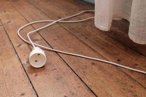 el cable de extensión eléctrico auténtico se encuentra en un antiguo suelo de madera vintage foto