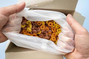 hands open a box of cereal corn rings photo