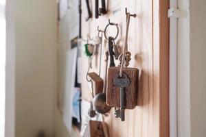 Vintage door key with a wooden keychain hangs on a hook on a board, on a blurred background. photo
