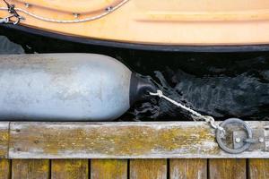 Marine fender tied with a rope to a metal ring on an old weathered pier protects the boat from damage. Top view. photo