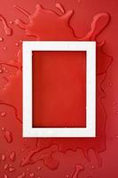 White rectangular empty frame on clean spilled water, on a red background. Copy space. Flat lay. Top view. photo