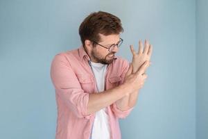 el joven está experimentando un dolor severo en el brazo, está masajeando el punto dolorido y apretando los dientes en el sufrimiento. concepto médico. foto