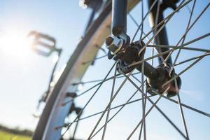 detalle de primer plano de una bicicleta estacionada en un prado, contra el telón de fondo del sol y el cielo azul. concepto de estilo de vida activo. vista inferior. foto