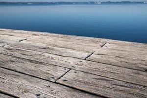 Old wooden pier made of weathered boards with nails, against the backdrop of a lake. Copy space. photo