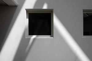 window with rays of light on a white wall and shadows photo