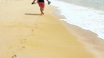 blootsvoets vrouw wandelen Aan een strand met sandalen in hand, mai khao strand, phuket video