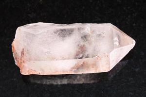 cristal crudo de piedra preciosa de cuarzo rosa en la oscuridad foto