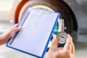 A man hold air pressure gauge check tire air pressure and memo in checklist in service check of car basic maintenance photo