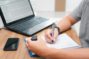 Business car service concept , a man use pen write on document file about the cost of repairing the car from the price of spare parts that must be replaced from stock and hold toy car in hand photo