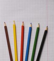 Blank paper and colorful pencils. Colored pencils on a notebook sheet. School notebook. View from above. photo