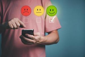 Customer service and Satisfaction survey concept ,Business people are touching the virtual screen on the happy Smiling face icon to give satisfaction in service. rating very impressed. photo