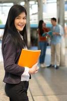 Young Asian woman holding books and smiling looking at camera in the university, people education concept. photo