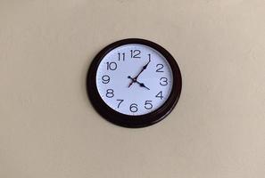 A black round clock with a white dial on a light wall. photo