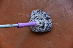 A mop for cleaning the floor in an old building. Feet and a mop for washing the floor. photo