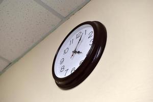 un reloj redondo negro con una esfera blanca en una pared clara. foto