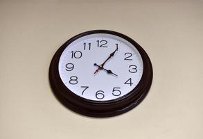 A black round clock with a white dial on a light wall. photo