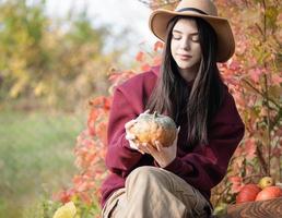 Happy young girl with pumpkin in autumn garden photo