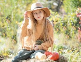 niña en el heno con calabazas foto