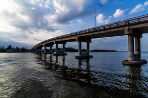 The image of beautiful rain clouds gathered in motion over the bridge over the river photo