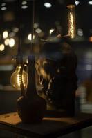 Sculpture of head with lamps. Jug on table. Incandescent lamps in interior. photo